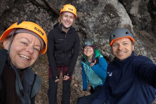 Vier Menschen mit Kletterhelmen stehen vor einer Felswand und lächeln in die Kamera. | © Toni Wegscheider