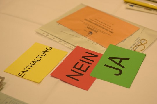 Abstimmungskarten in gelb für Enthaltung, rot für nein und grün für ja. In orange liegen die Wahlunterlagen | © Hermann Rupp
