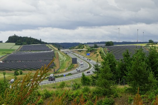 Autobahn umringt von Solarzellen, in der Fernen Windräder | © Peter Bria