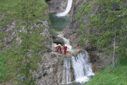 Zwei Menschen in roter Ausrüstung stehen an einem Wasserfall in den Bergen | © Hans-Joachim Fünfstück