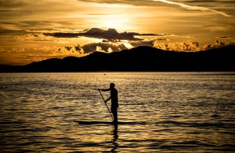 Schwarze Silhouette eines Mannes auf einem Stand Up Paddling Brett im Sonnenuntergang auf einem See | © pixabay