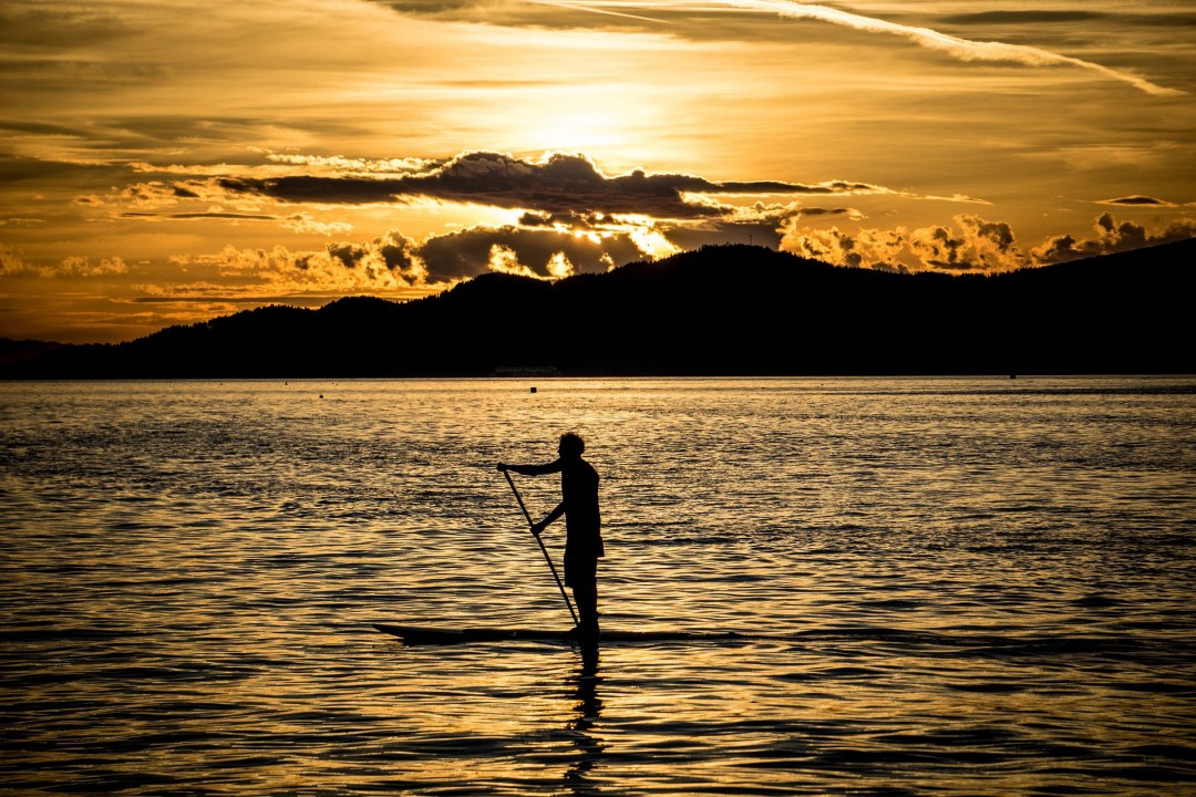 Schwarze Silhouette eines Mannes auf einem Stand Up Paddling Brett im Sonnenuntergang auf einem See | © pixabay