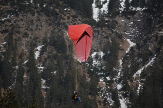 Gleitschirmflieger in den Bergen, der Schirm ist rot | © Henning Werth