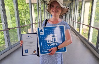 Elisabeth Hofer mit der Auszeichnung „Vogelfreundliche Glasfläche“ im nachgerüsteten Kaltgang der Uni Regensburg | © Dr. Peter Stimmler
